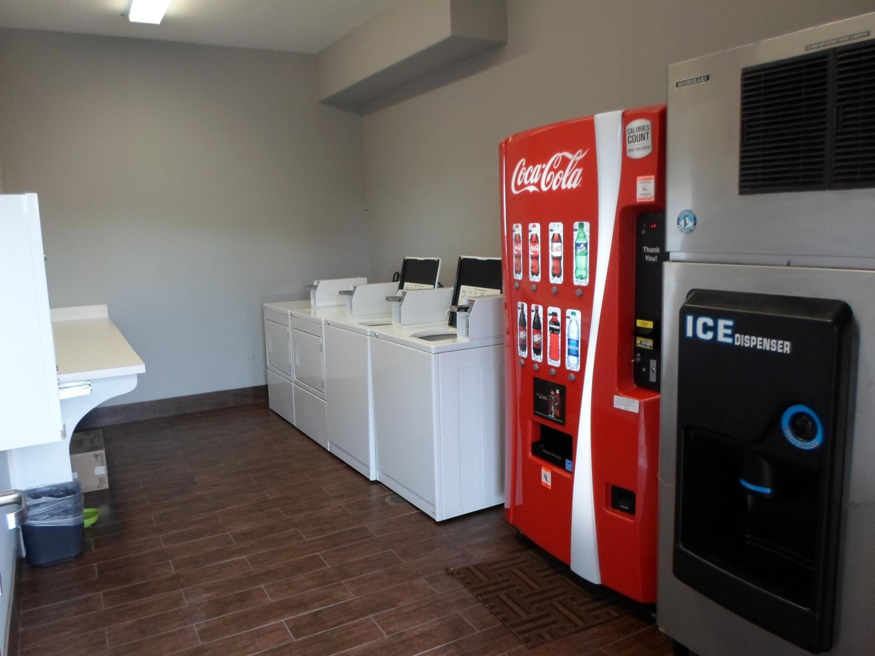 Habitación con lavadora, refrigerador Coca-Cola y dispensador de hielo.