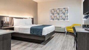 Camera d'albergo moderna con un letto, un comodino, una lampada, un condizionatore d'aria e una sedia gialla.