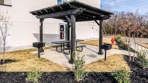 Un'area picnic riparata con panchine e cestini, un idrante e un edificio sullo sfondo.