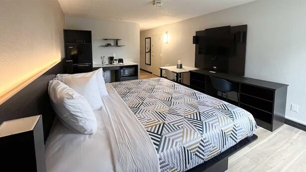 A modern hotel room with a large bed, a desk, a flat-screen TV, and a microwave. - Budget-Friendly Room | Free Parking, Pets Allowed | Durst Taylor Museum - 2.4 mi (Nacogdoches)