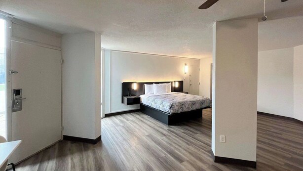 A modern hotel room with a bed, bedside tables, and a ceiling fan. - Budget & Pet-Friendly Room | Free Parking | Durst Taylor Museum - 2.4 miles (Nacogdoches)