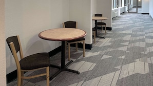 A corridor with carpeted flooring, a series of tables and chairs, and a glass door leading to another area. - Budget & Pet-Friendly Room | Free Parking | Durst Taylor Museum - 2.4 miles (Nacogdoches)