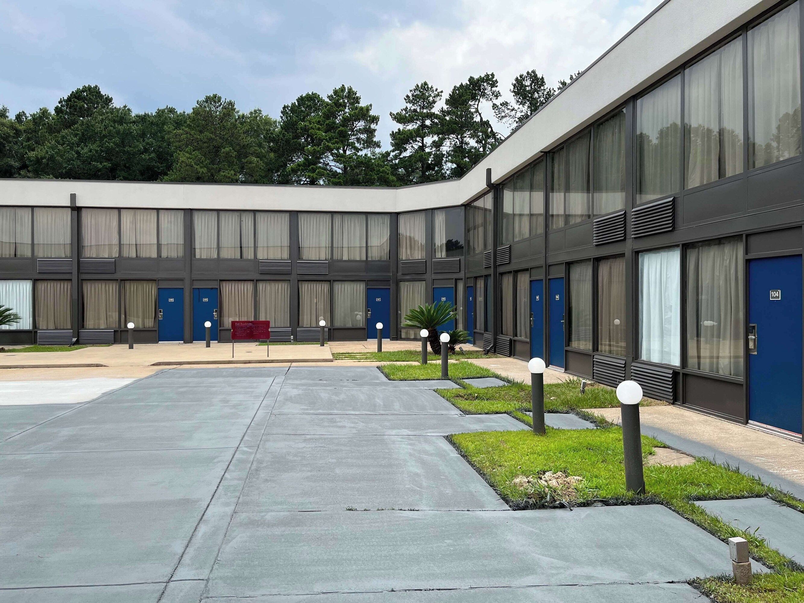 Un bâtiment moderne doté d’une cour intérieure, de grandes fenêtres et d’une porte bleue portant l’inscription « 104 ».