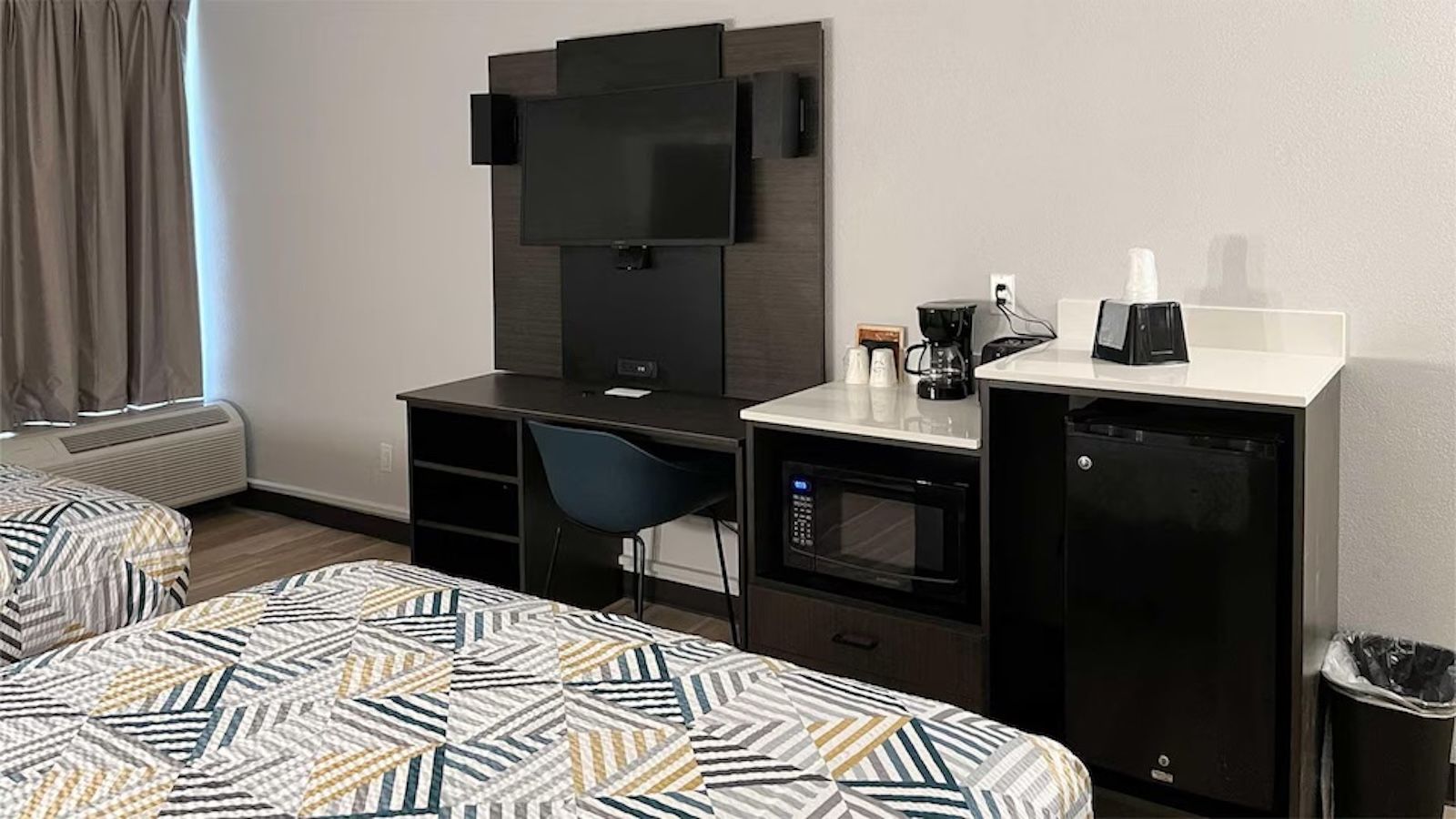 Une chambre d’hôtel avec deux lits, un bureau, une chaise, une télévision, un four à micro-ondes et une machine à café.