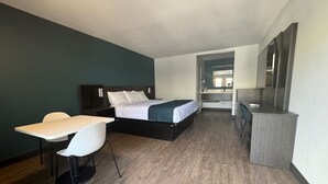 A hotel room with a bed, a desk, a chair, and a small kitchenette. - Modern Room w/ Free Parking | Redondo Beach Station - 3 miles away (Gardena)