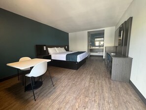 Een hotelkamer met een bed, een bureau, een stoel en een kleine kitchenette.
