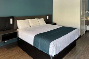 A modern hotel room with a large bed, bedside tables, and a wardrobe.