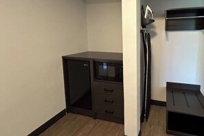 A small, dark-colored room with a desk, a chair, and a shelving unit against the wall.
