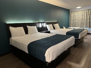 Een hotelkamer met twee bedden, donkere hoofdeinden en een klein tafeltje.