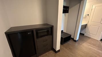 Una habitación compacta con kitchenette, microondas y un mueble pequeño.