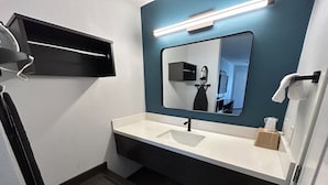 Ein modernes Badezimmer mit einem weißen Waschbecken, einem Spiegel und einem Handtuchhalter.