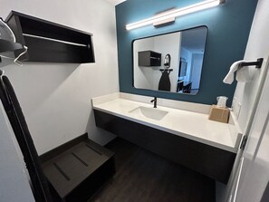 Een moderne badkamer met een witte wastafel, een spiegel en een handdoekhouder.