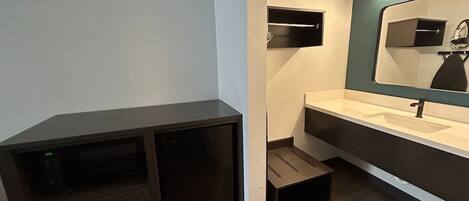 Une salle de bain moderne avec un meuble sombre, un lavabo et un miroir.