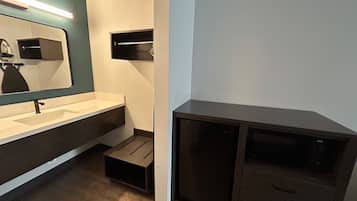 Un baño moderno con lavamanos, espejo y muebles oscuros.