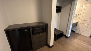 Une pièce compacte comprenant une kitchenette, un four à micro-ondes et un petit placard.