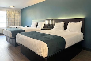 Een hotelkamer met twee bedden, een bureau en een groot raam met gordijnen.