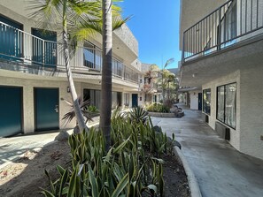 A courtyard with a central walkway, surrounded by buildings with balconies and windows.
