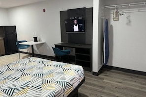 Ein Hotelzimmer mit einem Bett, einem Schreibtisch, einem Fernseher, einem Sessel und einem Kleiderschrank.