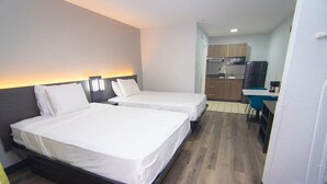 Hotellihuone, jossa on kaksi sänkyä, pieni keittotila ja pieni ruokailualue.