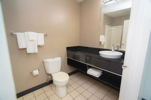 Un bagno con il water, un lavandino, uno specchio e un porta asciugamani.
