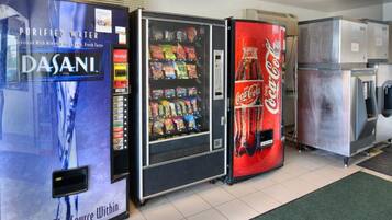 Zona de máquinas expendedoras con dispensador de agua Dasani, máquina de aperitivos y refrigerador de Coca-Cola.