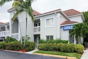 Un edificio a due piani con un cartello che riporta la scritta 'OFFICE' sul lato destro.