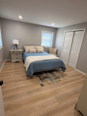 A bedroom with a bed, nightstand, lamp, window, and closet. - Peaceful 3-bedroom house with AC in charming La Porte, bring you peace and quiet (La Porte)