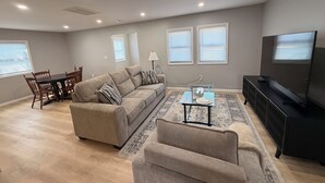 Una sala de estar con sofá, mesa de centro, televisor y una zona de comedor con sillas y mesa.