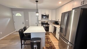 Una cocina moderna con armarios blancos, electrodomésticos de acero inoxidable y una isla central con asientos.