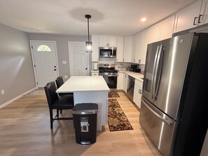 A modern kitchen with white cabinets, stainless steel appliances, and a central island with seating. - Peaceful 3-bedroom house with AC in charming La Porte, bring you peace and quiet (La Porte)