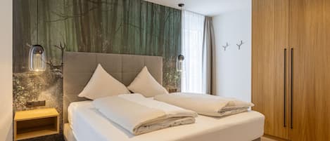 Un dormitorio con una cama, una mesita de noche, un armario y un papel tapiz con motivos naturales.