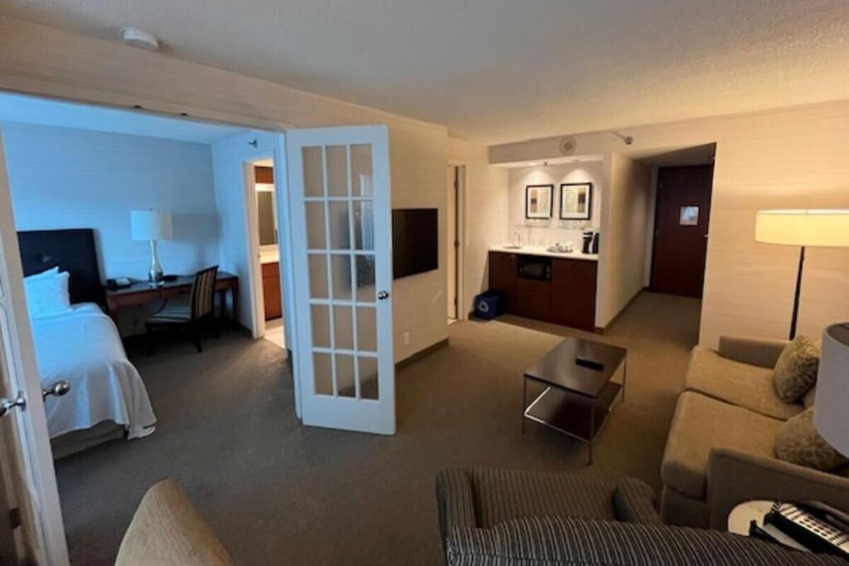 Een hotelkamer met een bed, een bureau, een stoel, een bank, een eettafel en een kitchenette.