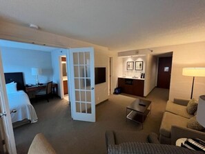 Een hotelkamer met een bed, een bureau, een stoel, een bank, een eettafel en een kitchenette.