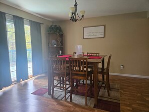 A dining area with a table, chairs, a chandelier, and a bookshelf.