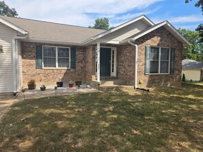 A residential house with a brick facade, a front porch, and a well-maintained lawn.