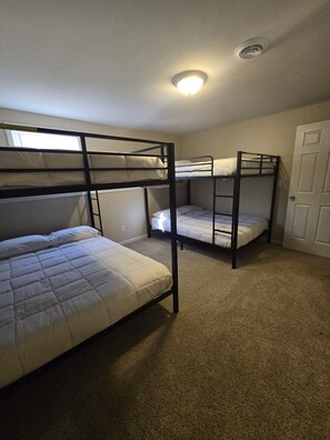 A room with bunk beds, carpeted floor, and a door.