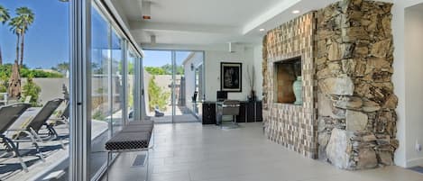 Un interior moderno con pared de piedra, un banco y una puerta de cristal que da al exterior.