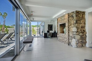 A modern interior with a stone wall, a bench, and a glass door leading outside. - The Cascades Retreat: 3 Bedroom Home with Private Pool and Mountain Views (Palm Springs)