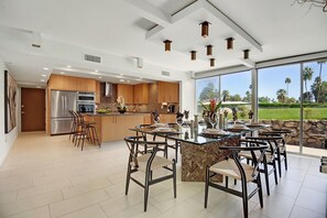 A modern kitchen with a dining area, large windows, and a view of the outdoors. - The Cascades Retreat: 3 Bedroom Home with Private Pool and Mountain Views (Palm Springs)