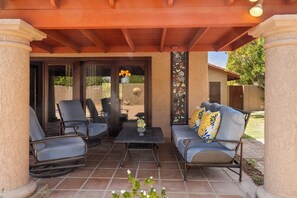 An outdoor patio with a covered seating area, a table, and a decorative wall. - Vista El Quetzal - Central Palm Springs (Palm Springs)