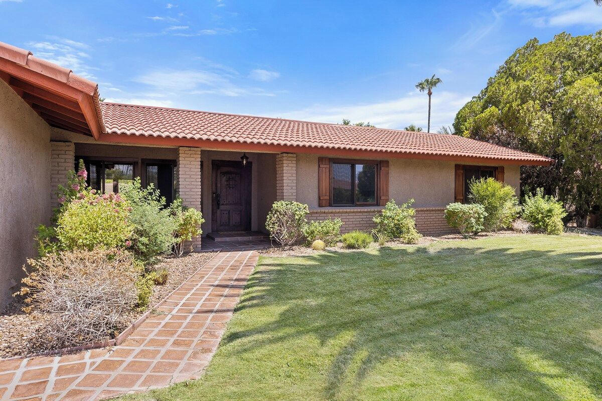 A single-story house with a red-tiled roof, a brick exterior, and a well-maintained lawn.