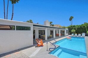 A modern pool area with a clear blue pool, lounge chairs, and a patio with outdoor seating. - Twin Palms Tranquility (Palm Springs)