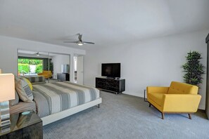 A modern bedroom with a bed, a television, a yellow armchair, and a large mirror. - Twin Palms Tranquility (Palm Springs)
