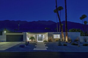 A modern house with a garage, a front door, and a driveway leading to the entrance. - Twin Palms Tranquility (Palm Springs)
