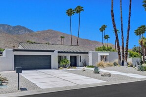 A modern two-story house with a garage, surrounded by desert landscaping and palm trees. - Twin Palms Tranquility (Palm Springs)