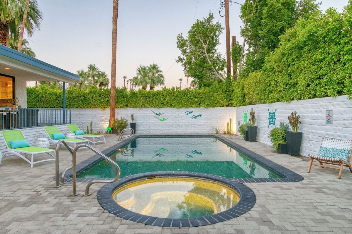 An outdoor swimming pool with lounge chairs and a wall with decorative tiles.