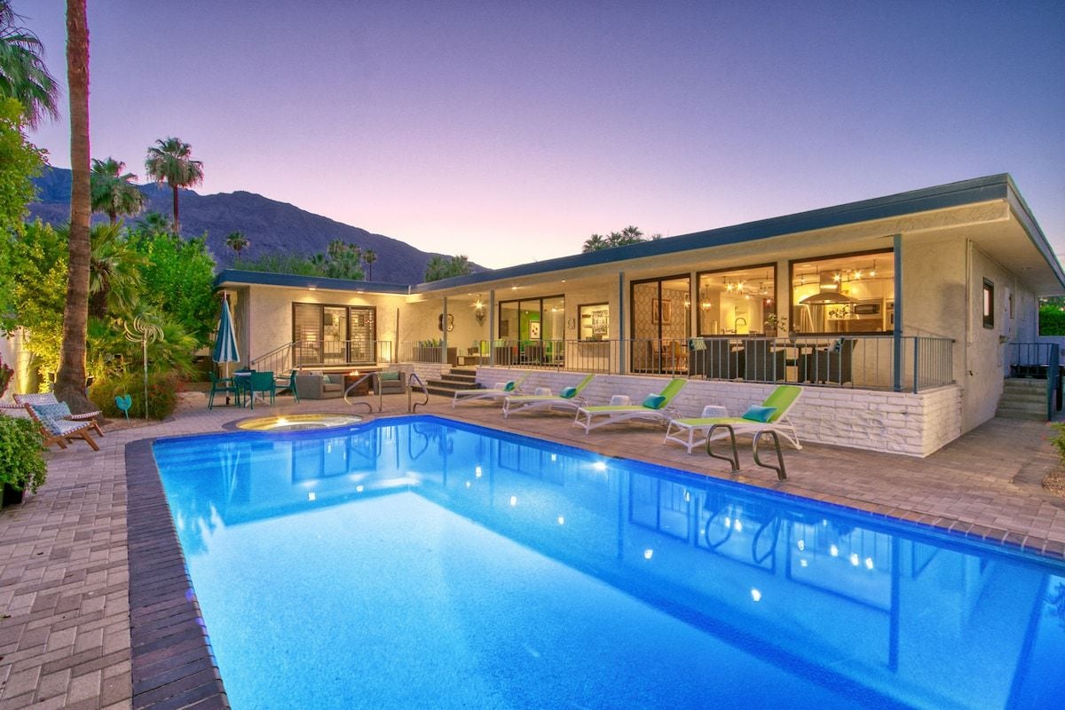 A modern house with a swimming pool, outdoor seating, and a mountain backdrop.