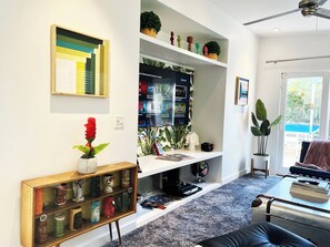 A living room with a flat-screen TV, a bookshelf, a coffee table, and a sofa. - Puerta Del Sol - Tahquitz River Estates (Palm Springs)
