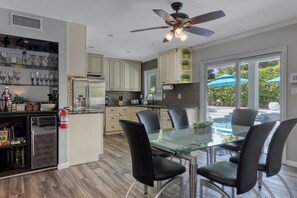 A modern kitchen with a glass dining table, black chairs, and a ceiling fan. - Vista Ranch Hideaway: Palm Springs Home with Private Pool and Mountain Views (Palm Springs)