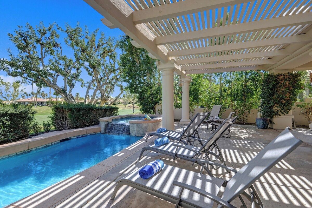 A pool area with lounge chairs and a pergola.